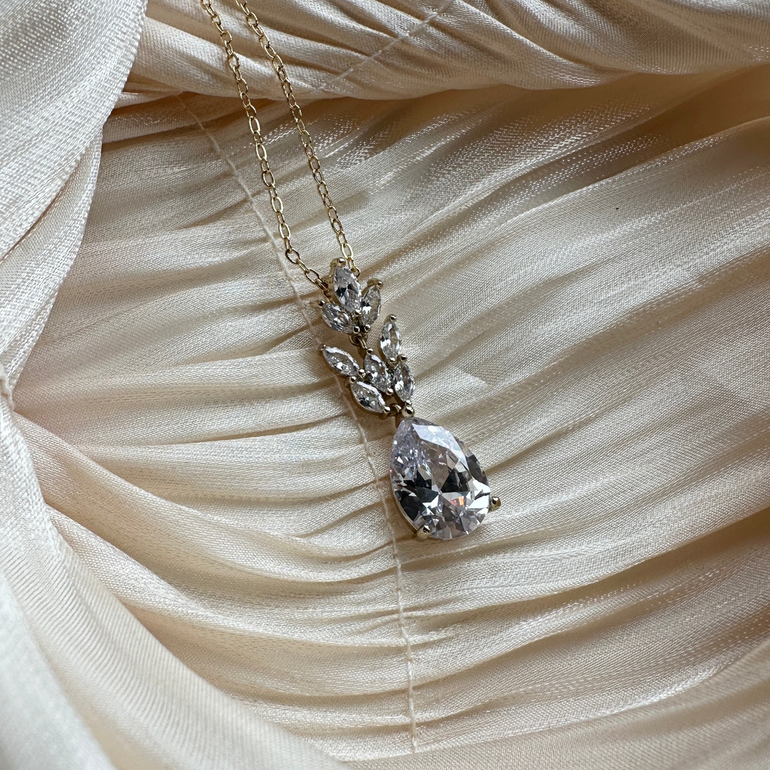 Gold necklace with a teardrop-cut crystal and marquise-cut stones in a floral-inspired design.