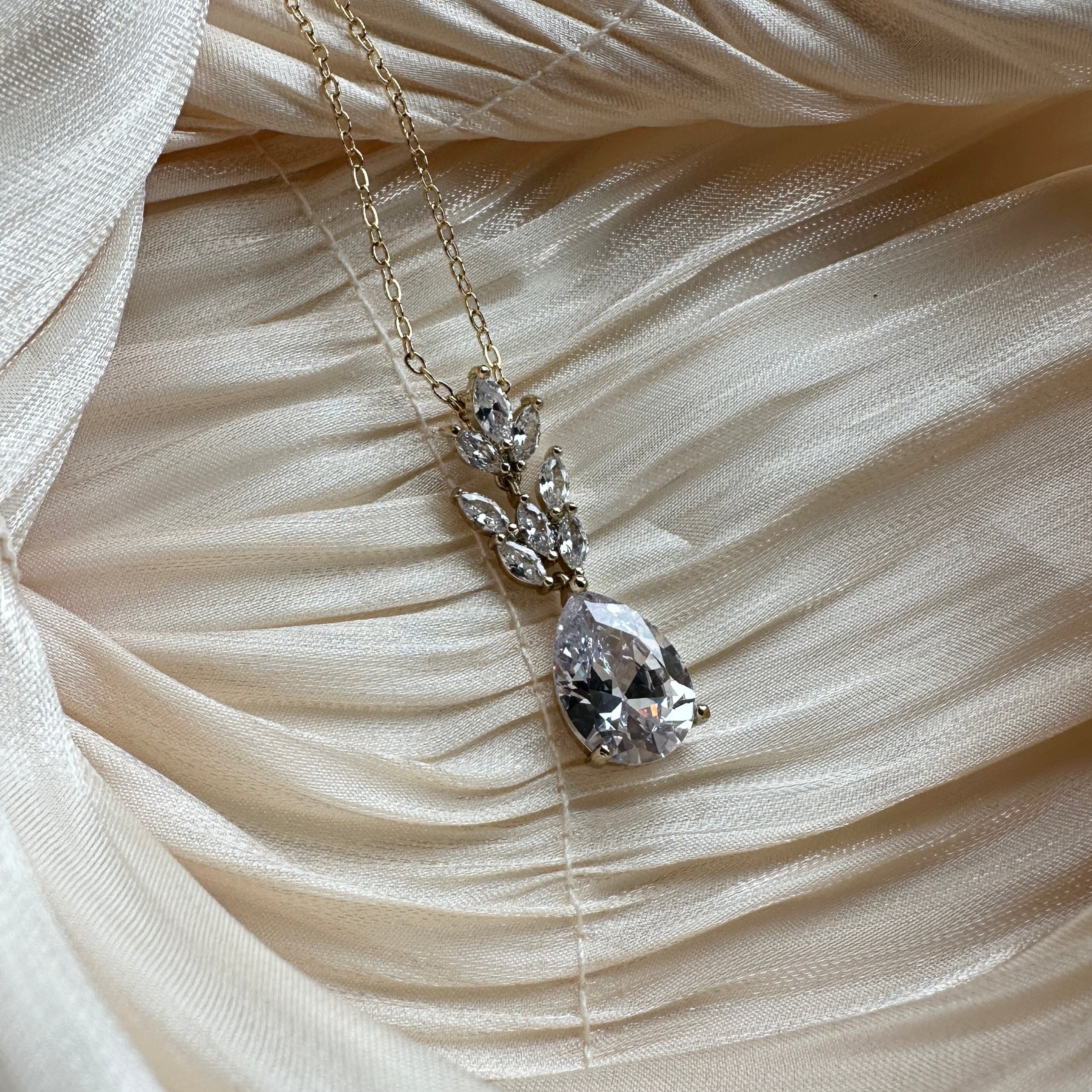 Gold necklace with a teardrop-cut crystal and marquise-cut stones in a floral-inspired design.