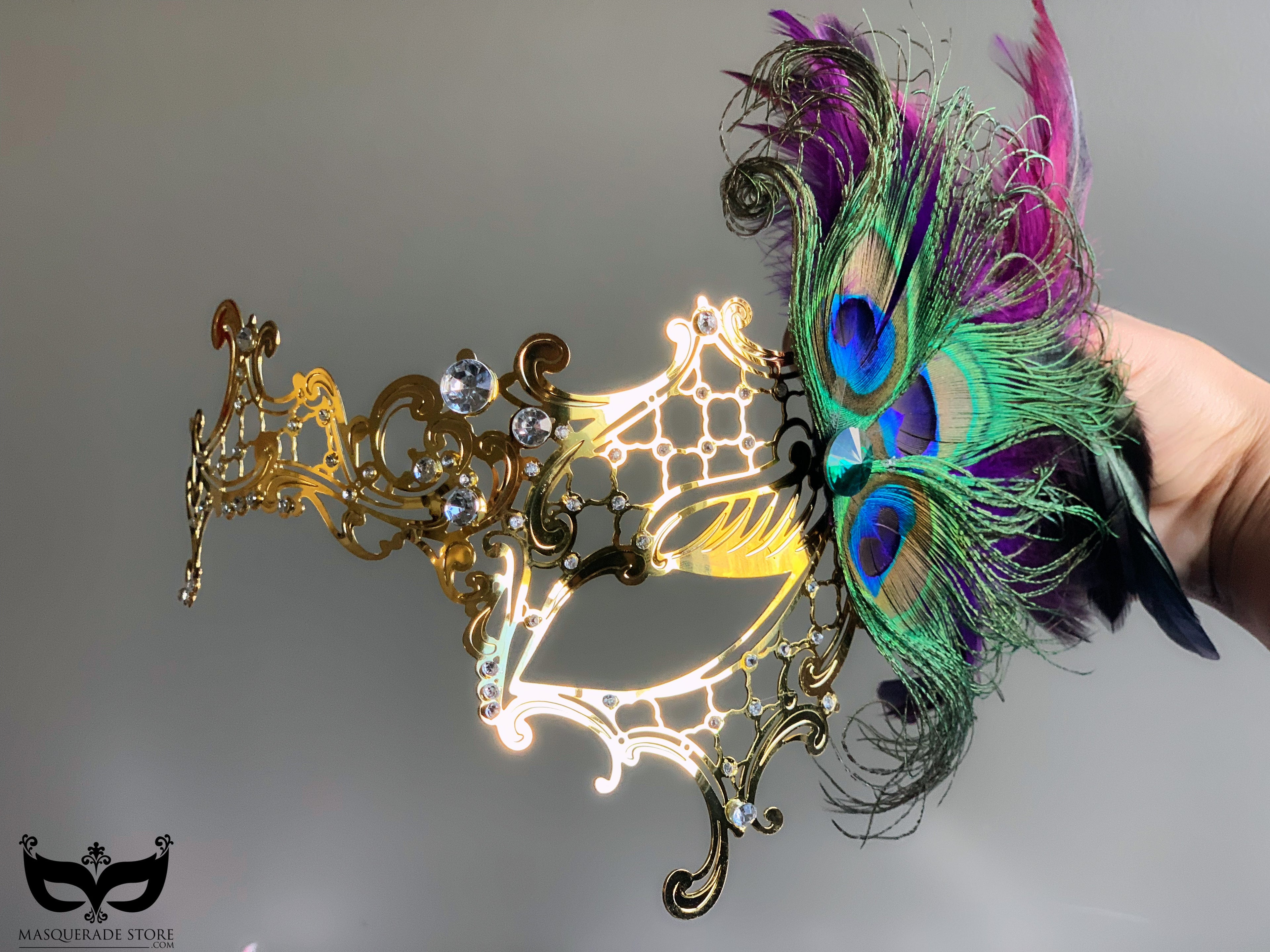 Gold metal mask with peacock and purple feathers, rhinestones, and intricate design