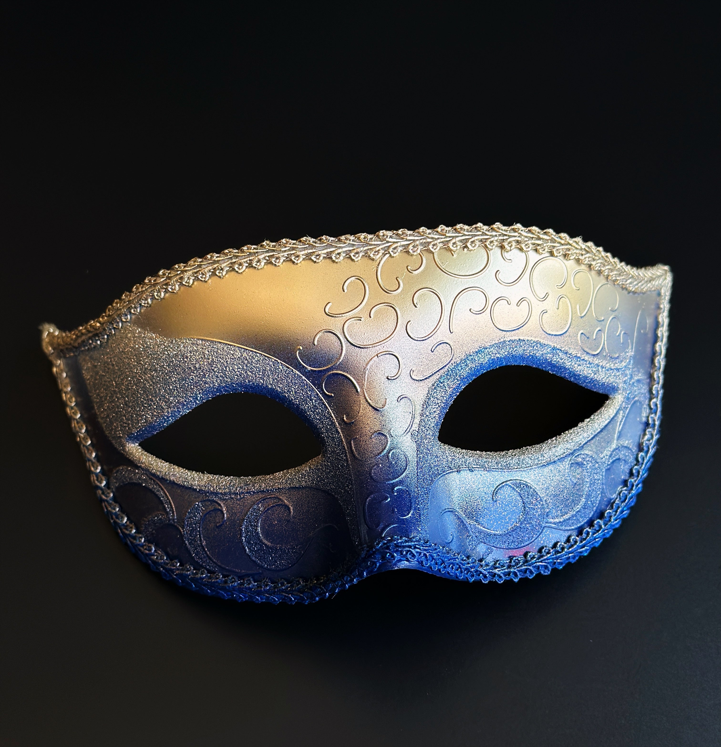 Gold and royal blue ombre Venetian masquerade eye mask with embossed Baroque scrollwork, metallic finish, decorative braided trim, and satin ribbon ties for masquerade balls, Mardi Gras celebrations, and gala events.