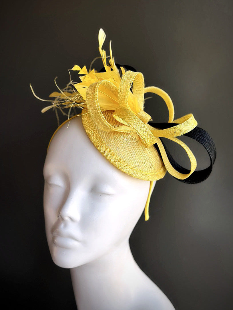 Yellow fascinator hat with bow, feather accents, and black ribbon