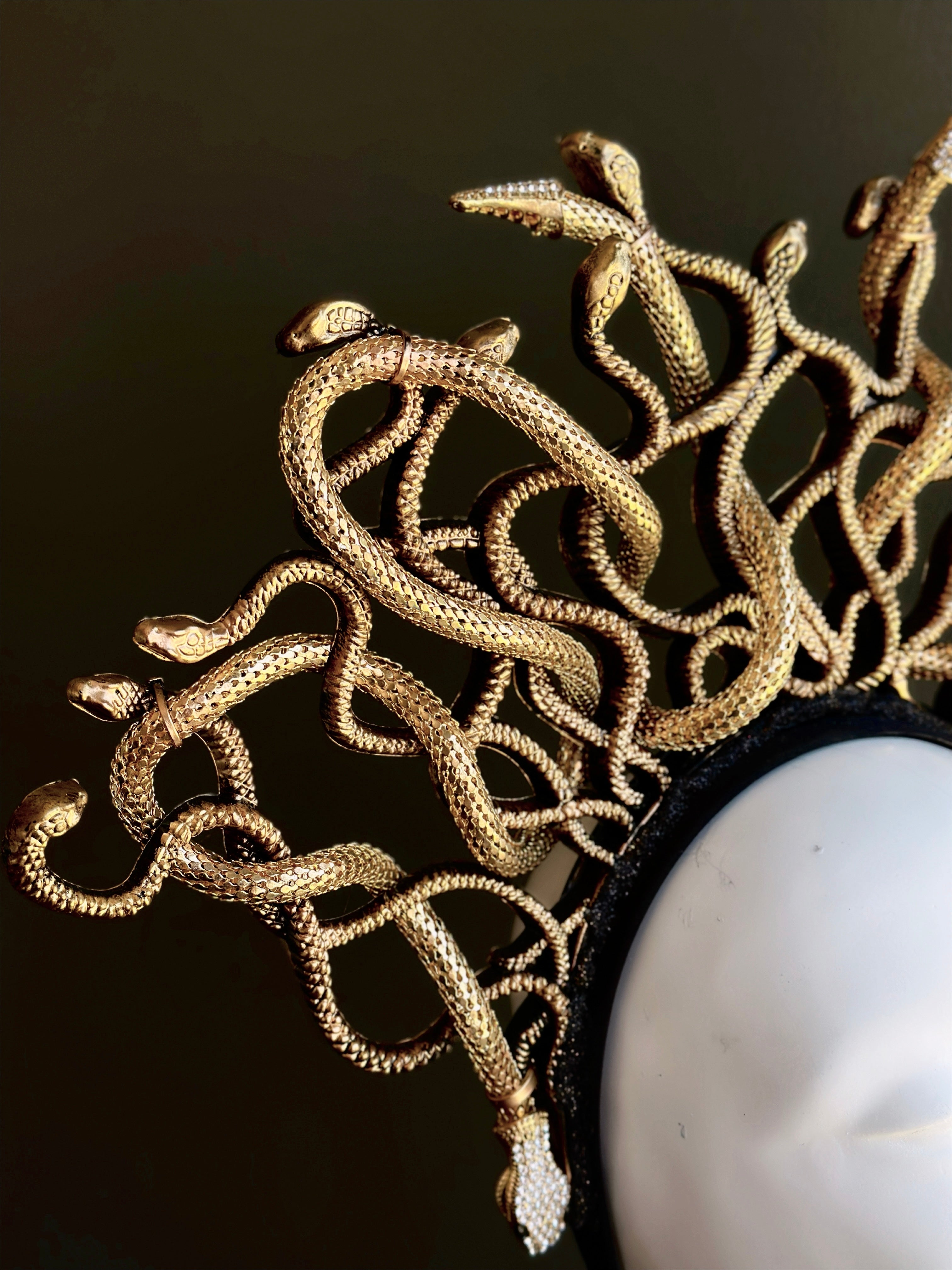 Side view of goddess Medusa crown headpiece adorned with curling gold serpents for dramatic effect