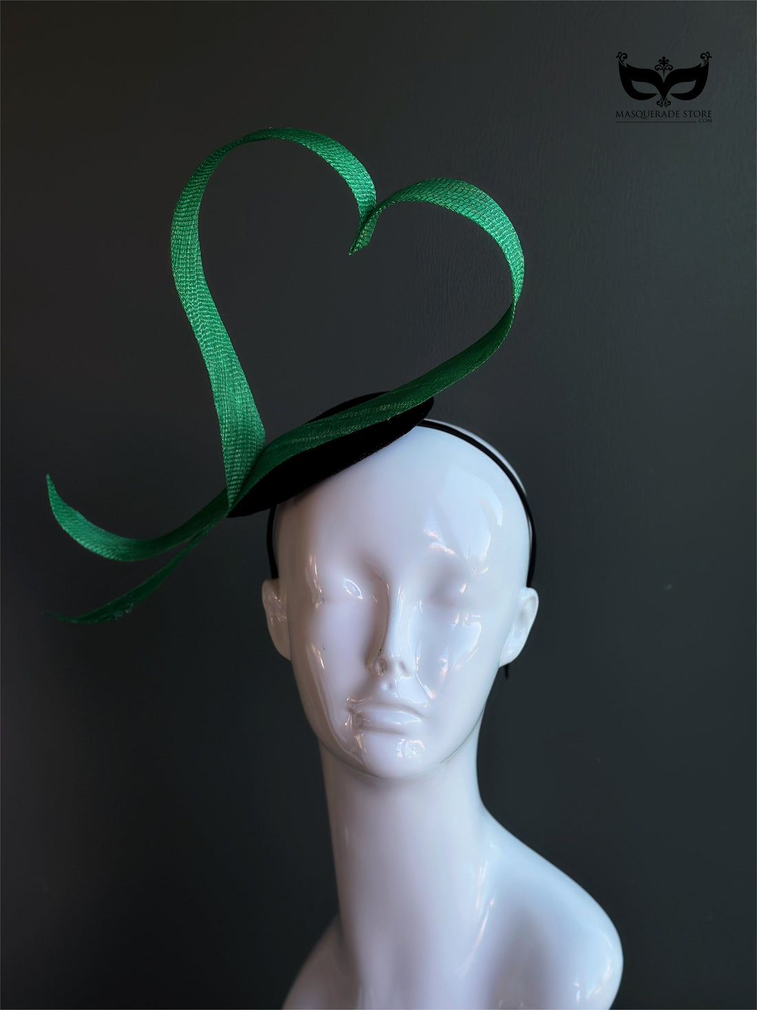 Green heart loop fascinator headband with sculptural ribbon design on mannequin