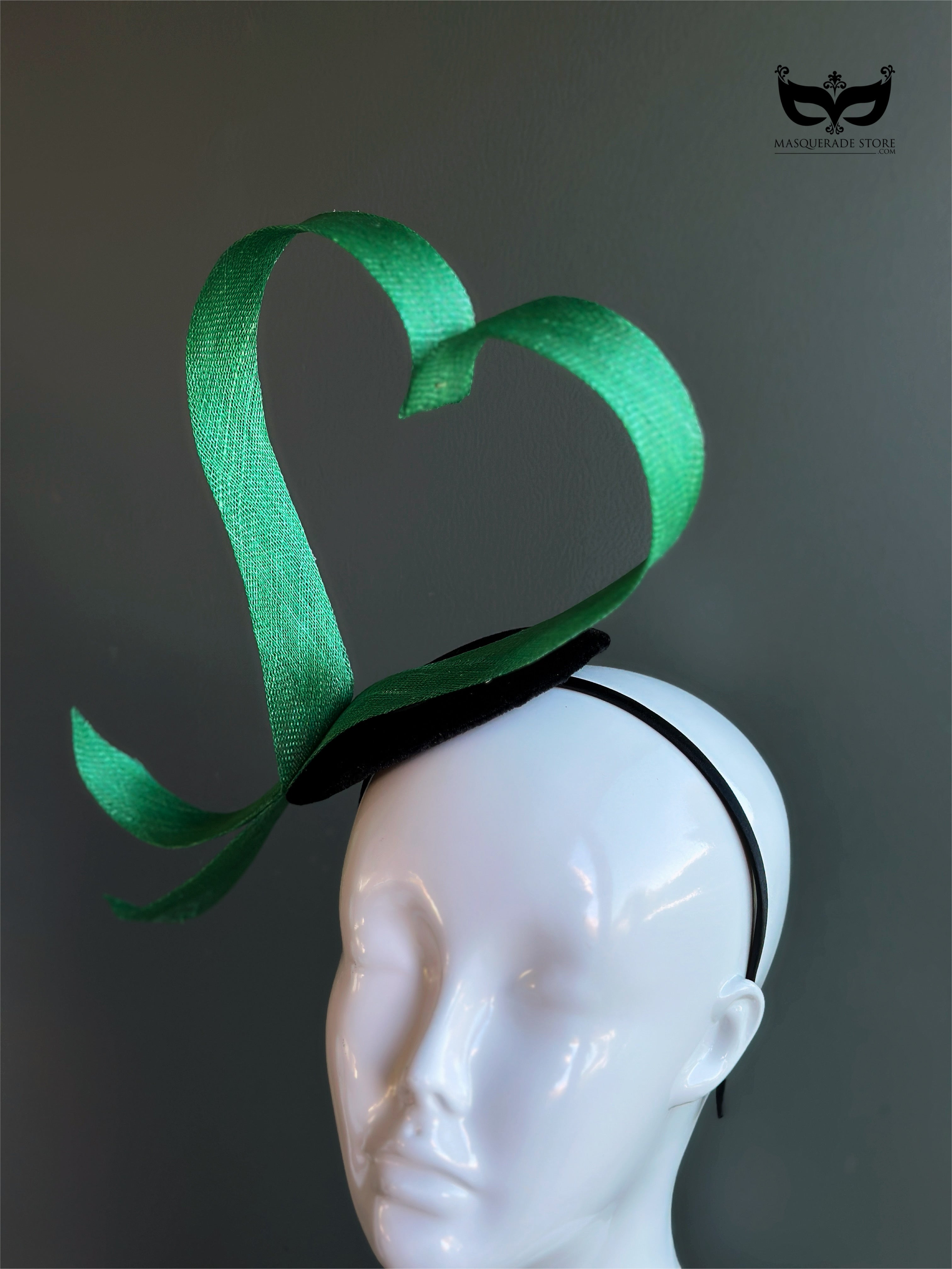 Green heart loop fascinator headband with sculptural ribbon design on mannequin