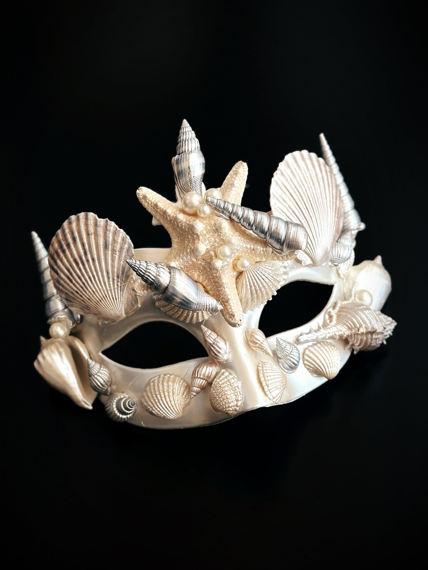 Ivory masquerade mask decorated with seashells, starfish, and pearls in a mermaid-inspired ocean theme.