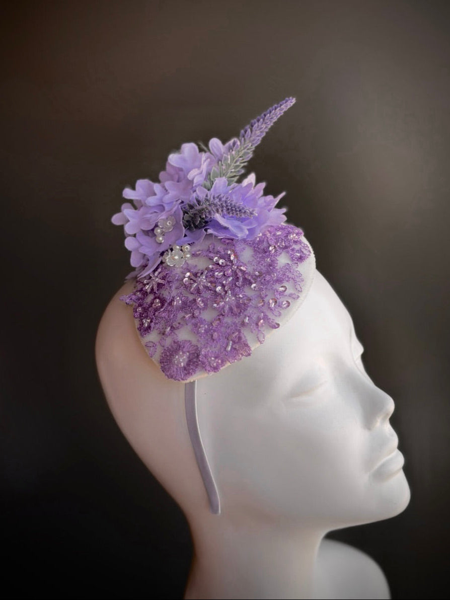 Lavender fascinator hat features florals, pearls, and lace