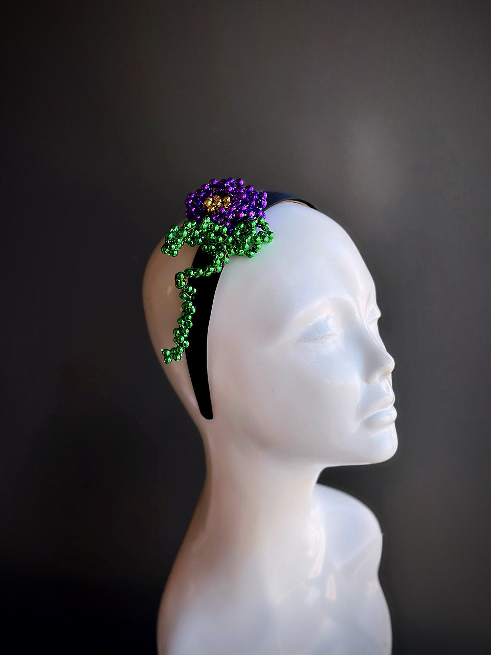 Mardi Gras beaded flower headband with purple, green, and gold accents displayed on a mannequin head.