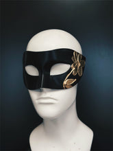Black masquerade mask with a gold hand-painted flower design.