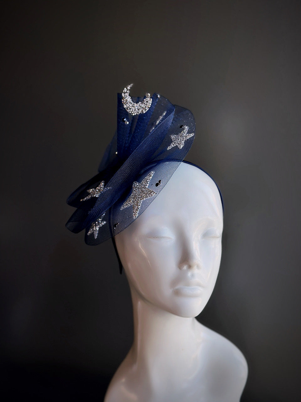Midnight blue fascinator with rhinestone moon and star embellishments displayed on a mannequin head.