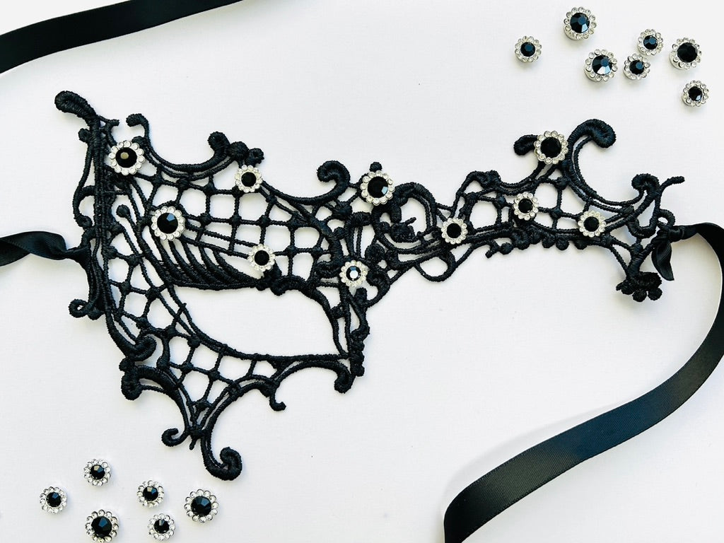 Black embroidered spiderweb lace masquerade mask with sparkling black rhinestones and satin ribbon ties. Perfect for Halloween, gothic costumes, masquerade balls, vampire cosplay, Venetian masquerade events, Mardi Gras celebrations, theatrical performances, gothic weddings, fantasy costumes, and elegant evening wear.