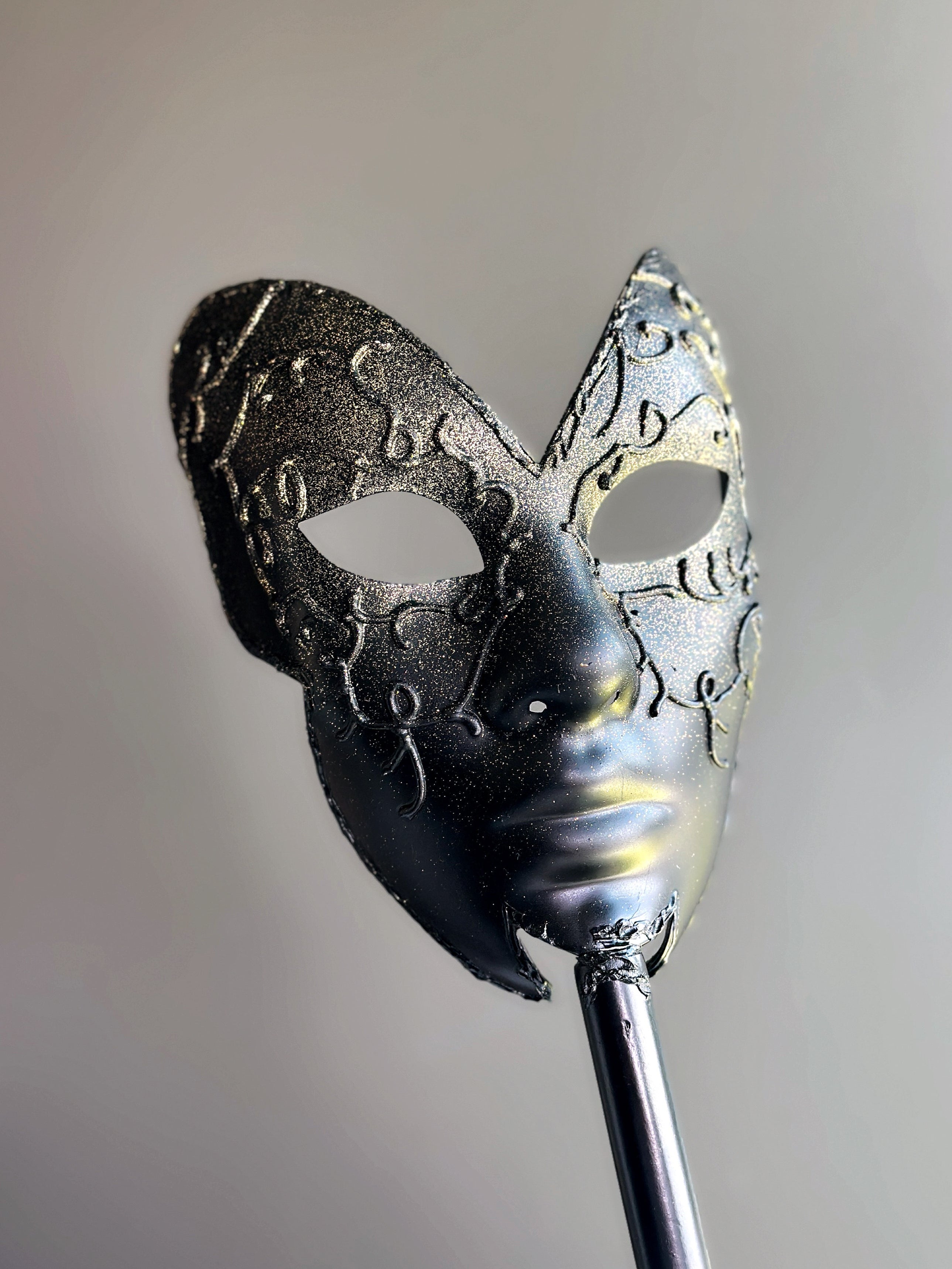 : Elegant black half-face masquerade mask on stick with glitter filigree