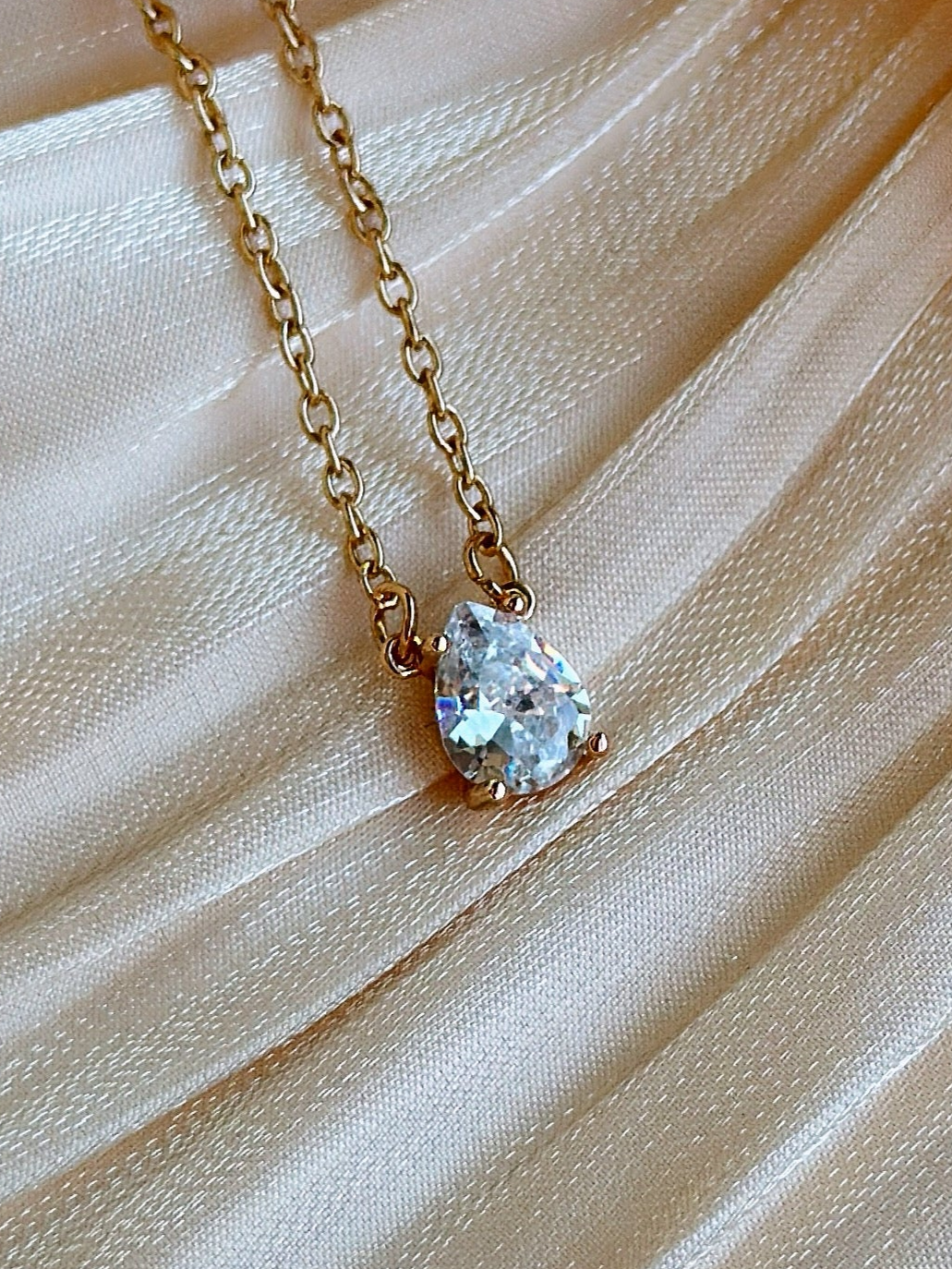 Clear pear cut crystal pendant on a gold plated chain.