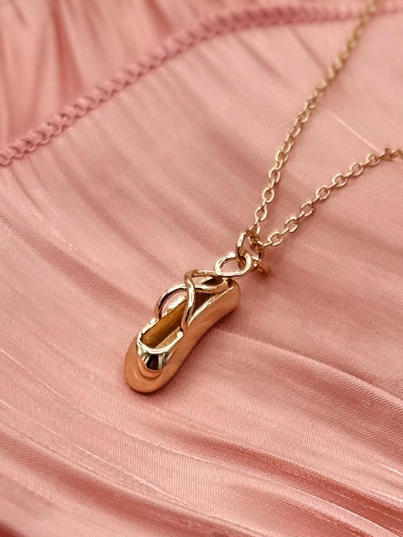 Gold ballet slipper necklace on a gold-plated necklace.