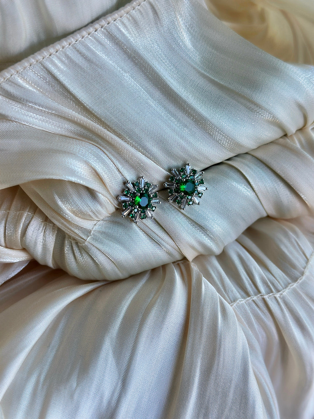 Radiant burst earrings with a green center stone and crystal accents.