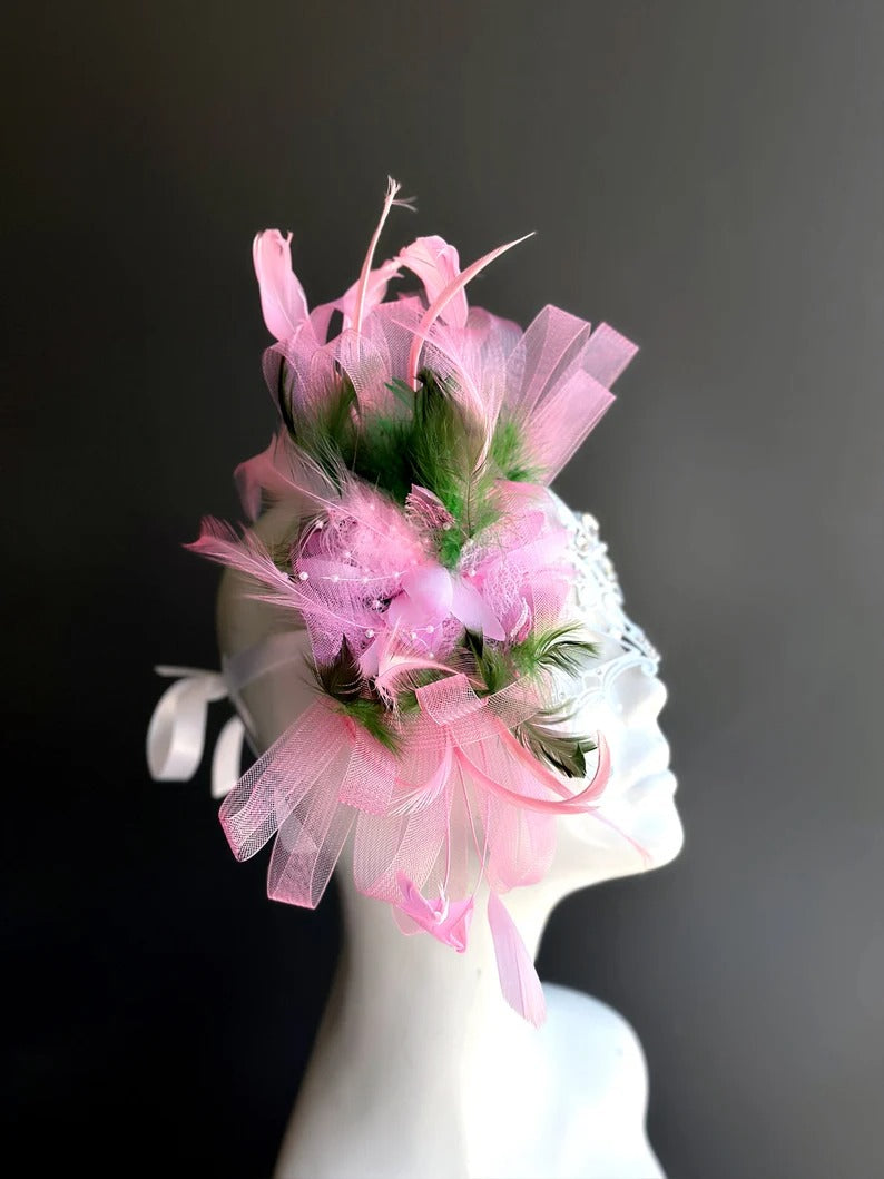 Elegant white lace masquerade mask with pink feathers and rhinestones for women’s prom, carnival, and party looks.