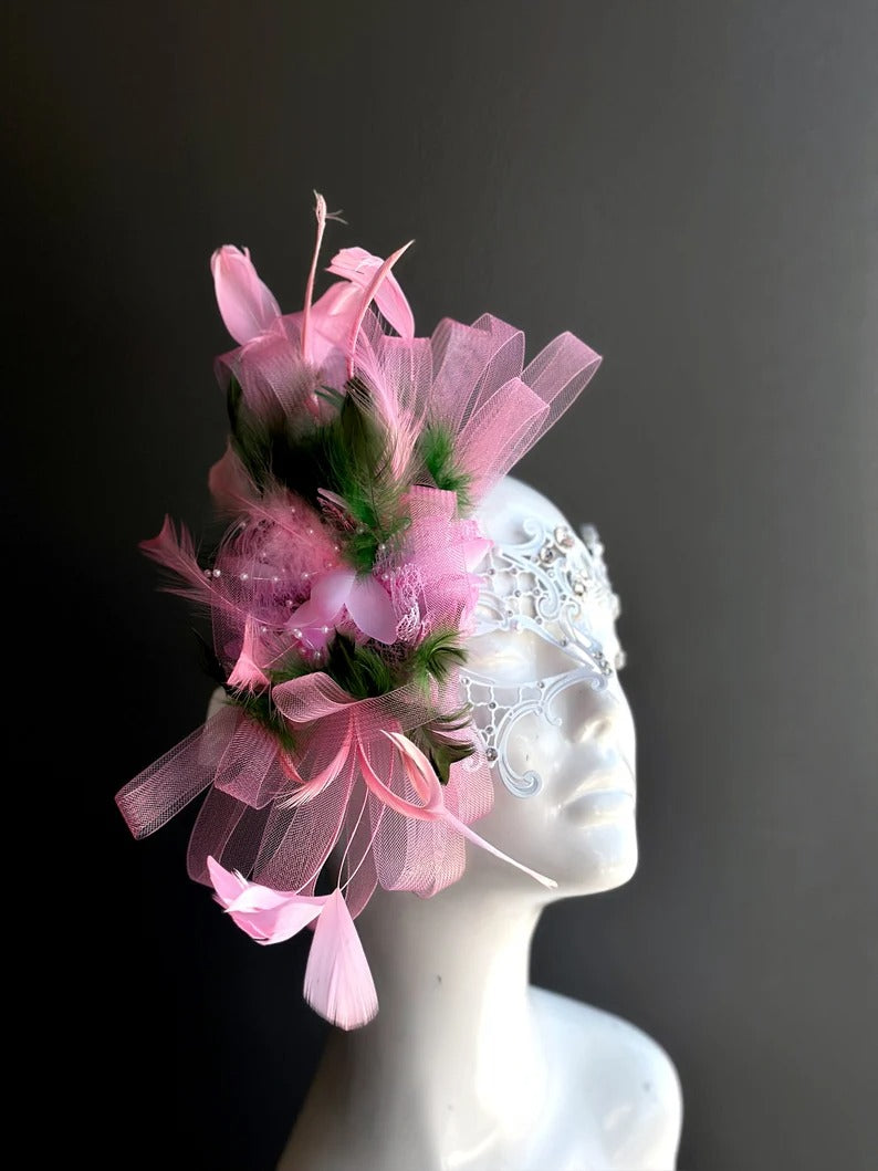 Elegant white lace masquerade mask with pink feathers and rhinestones for women’s prom, carnival, and party looks.
