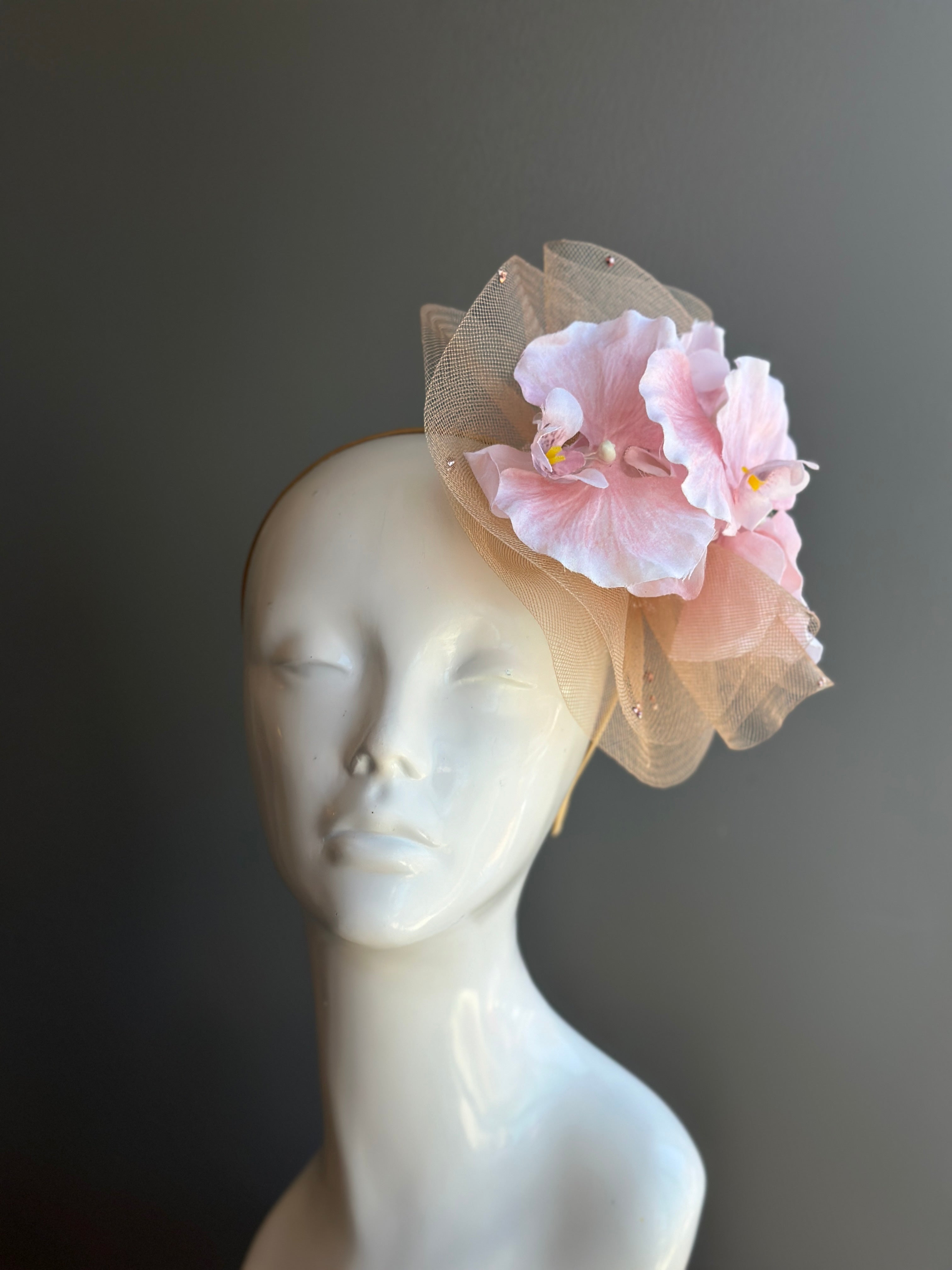 Blush pink fascinator with tulle and magnolia flowers, ideal for weddings and special occasions.