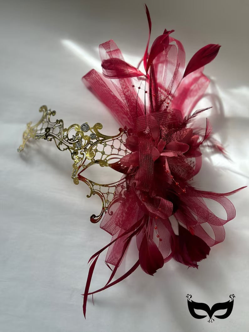 Elegant red and gold masquerade mask with feathers, ribbons, and rhinestones, perfect for Venetian masquerade balls and proms.