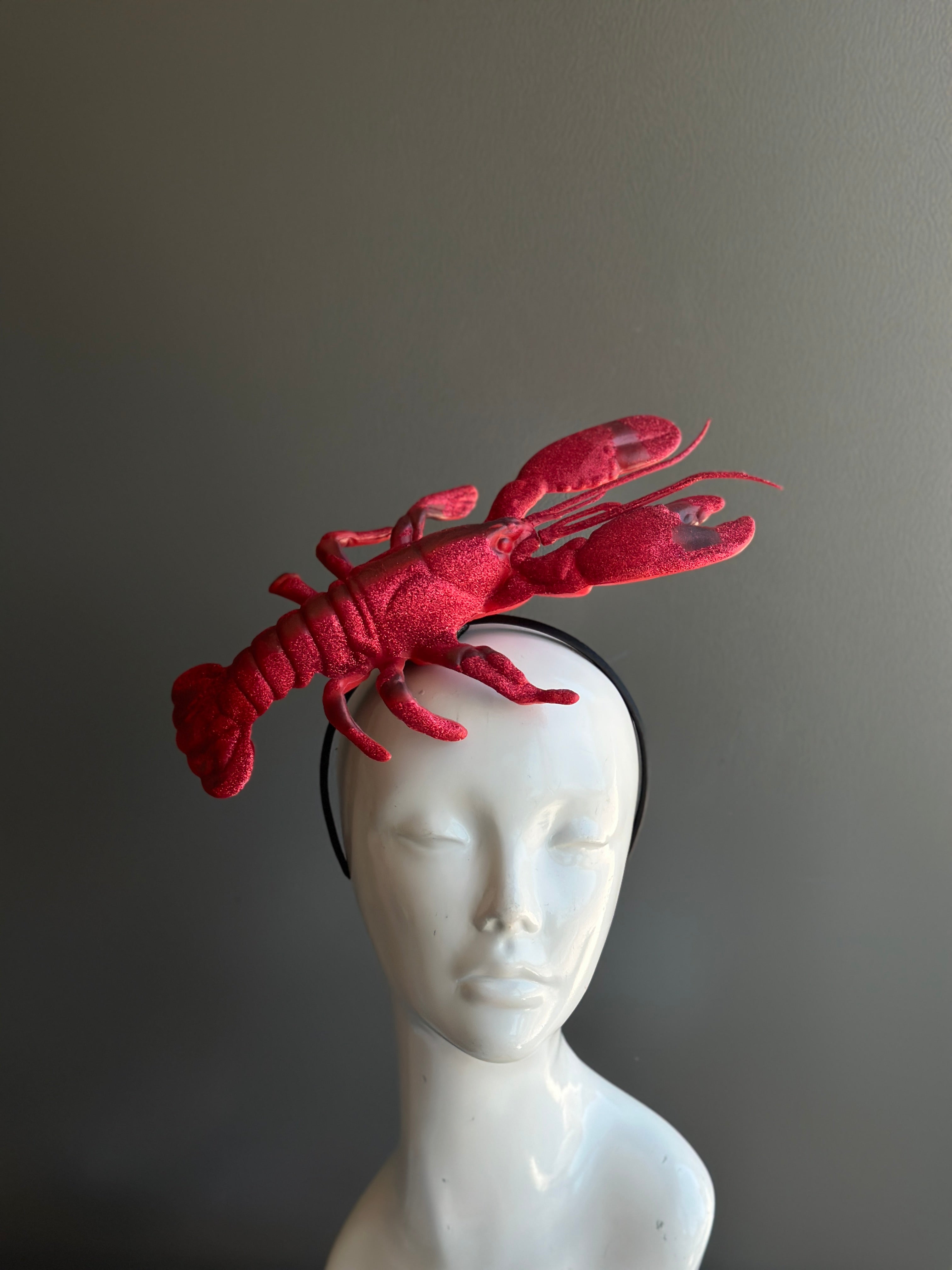 Red lobster fascinator headpiece, a fun and bold accessory for seafood-themed events and statement fashion.