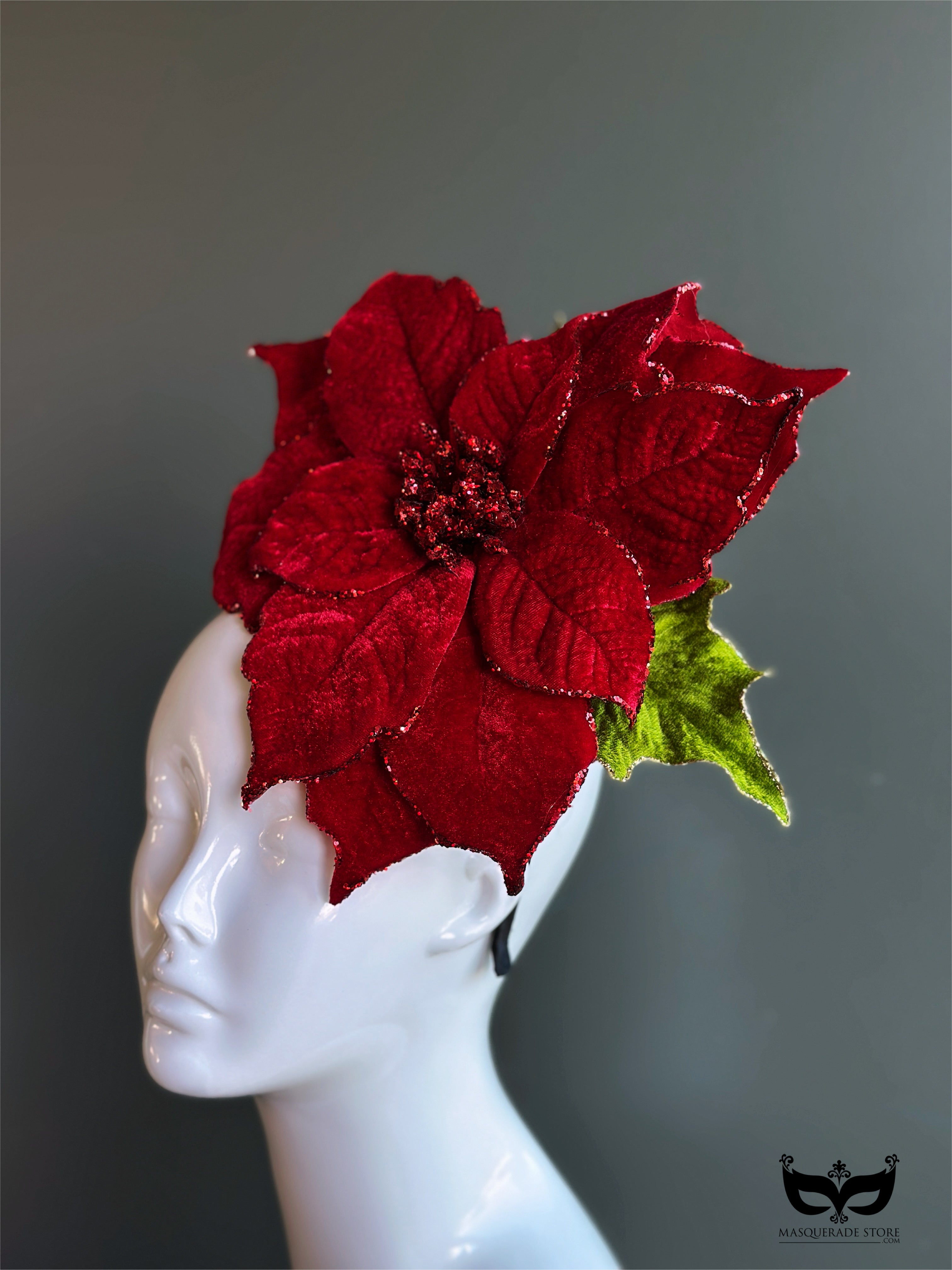 Red poinsettia holiday fascinator hat with layered velvet petals on mannequin