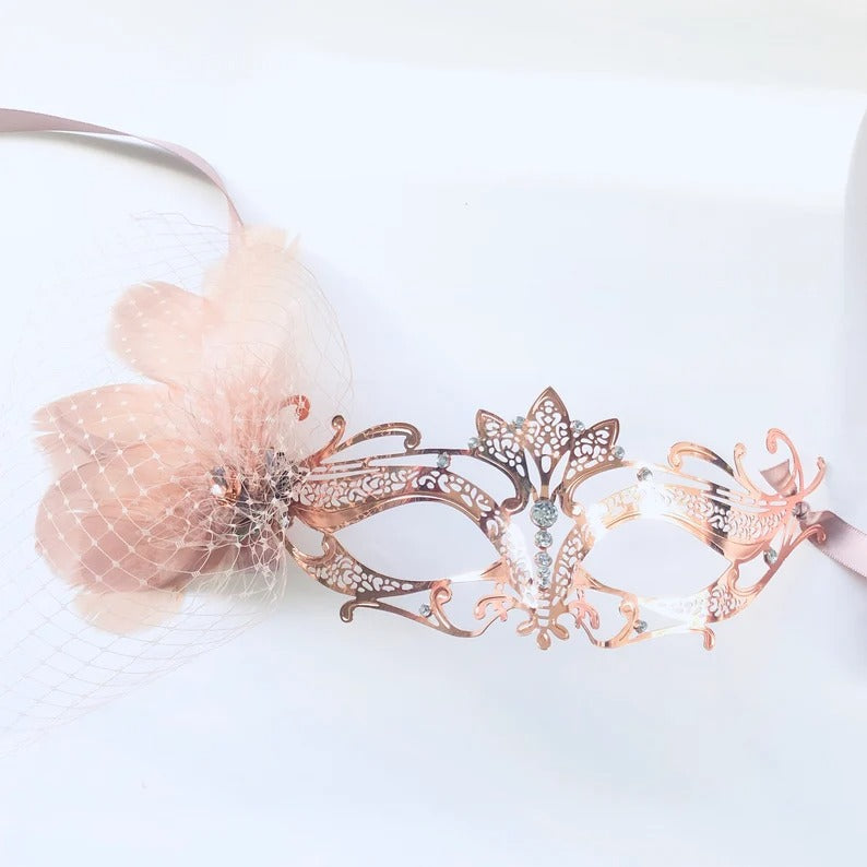 Elegant rose gold masquerade mask with filigree design, flower, netting, and rhinestones for weddings, Venetian balls, and prom parties.
