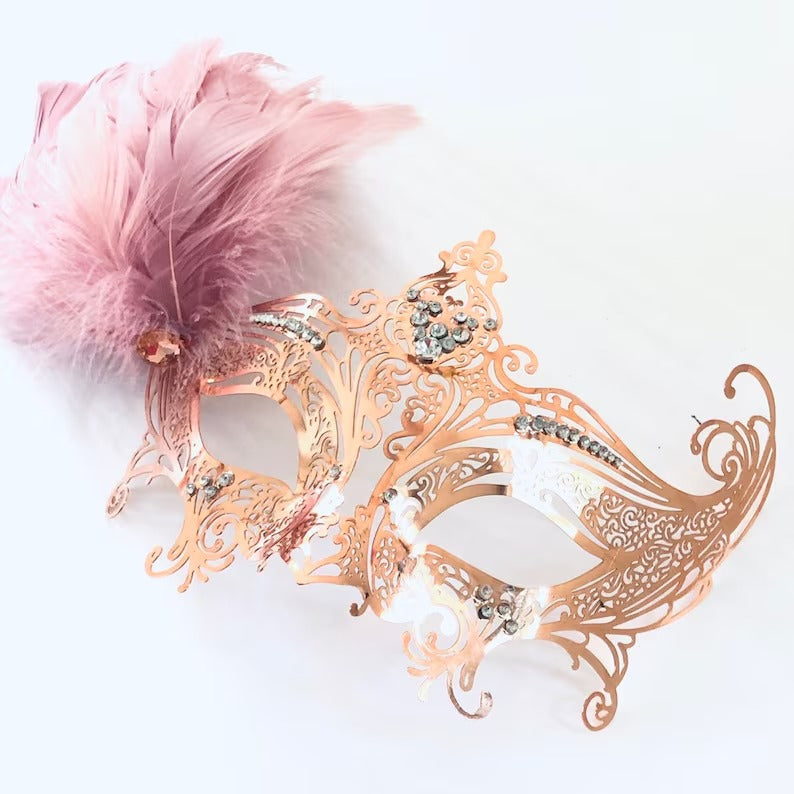Rose gold filigree masquerade mask with pink feather and rhinestone accents for weddings, proms, Venetian balls, and Mardi Gras parties.