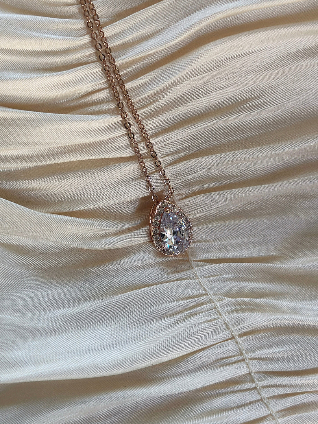 Rose gold teardrop pendant necklace with shimmering cubic zirconia on a delicate chain.