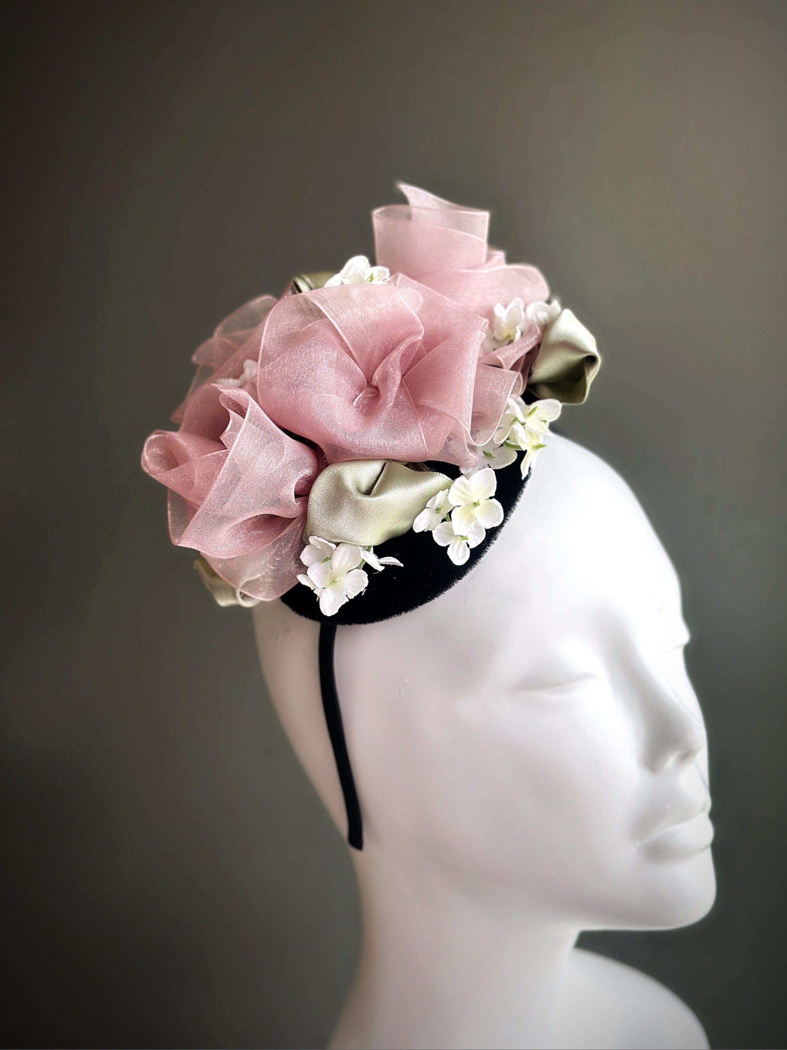 Romantic pink and ivory fascinator hat with floral accents and swirling ribbon