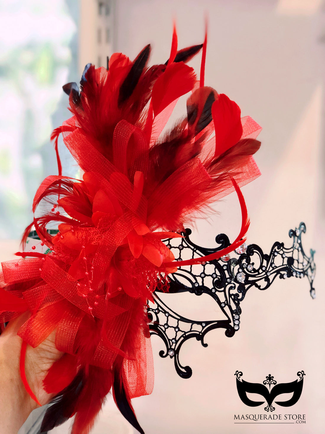 Black filigree masquerade mask with royal red tulle, feathers, and rhinestones for women.