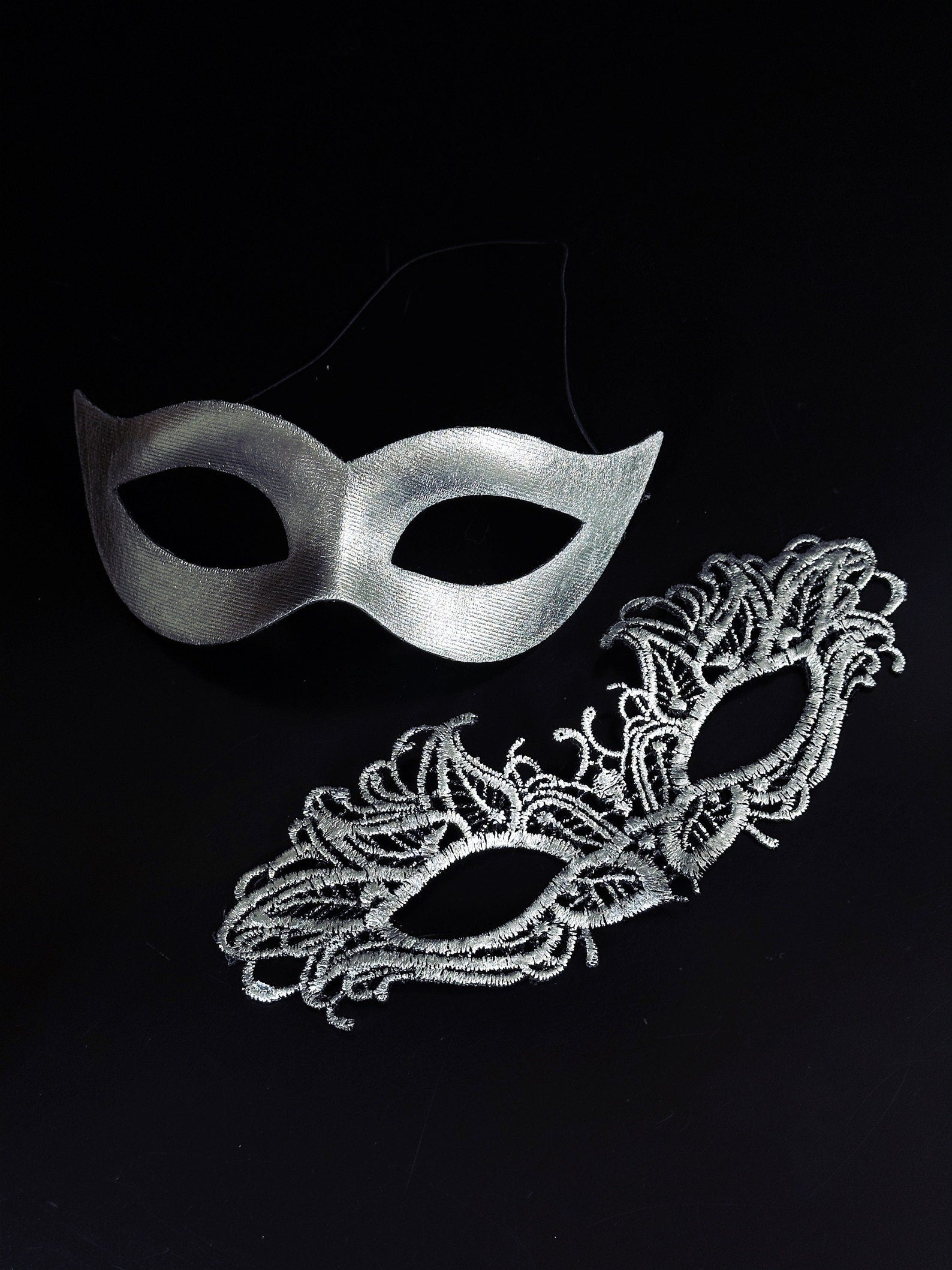 Elegant silver couples masquerade masks featuring a sleek cat-eye men’s mask and a delicate lace women’s mask, perfect for Venetian balls, weddings, and themed celebrations.