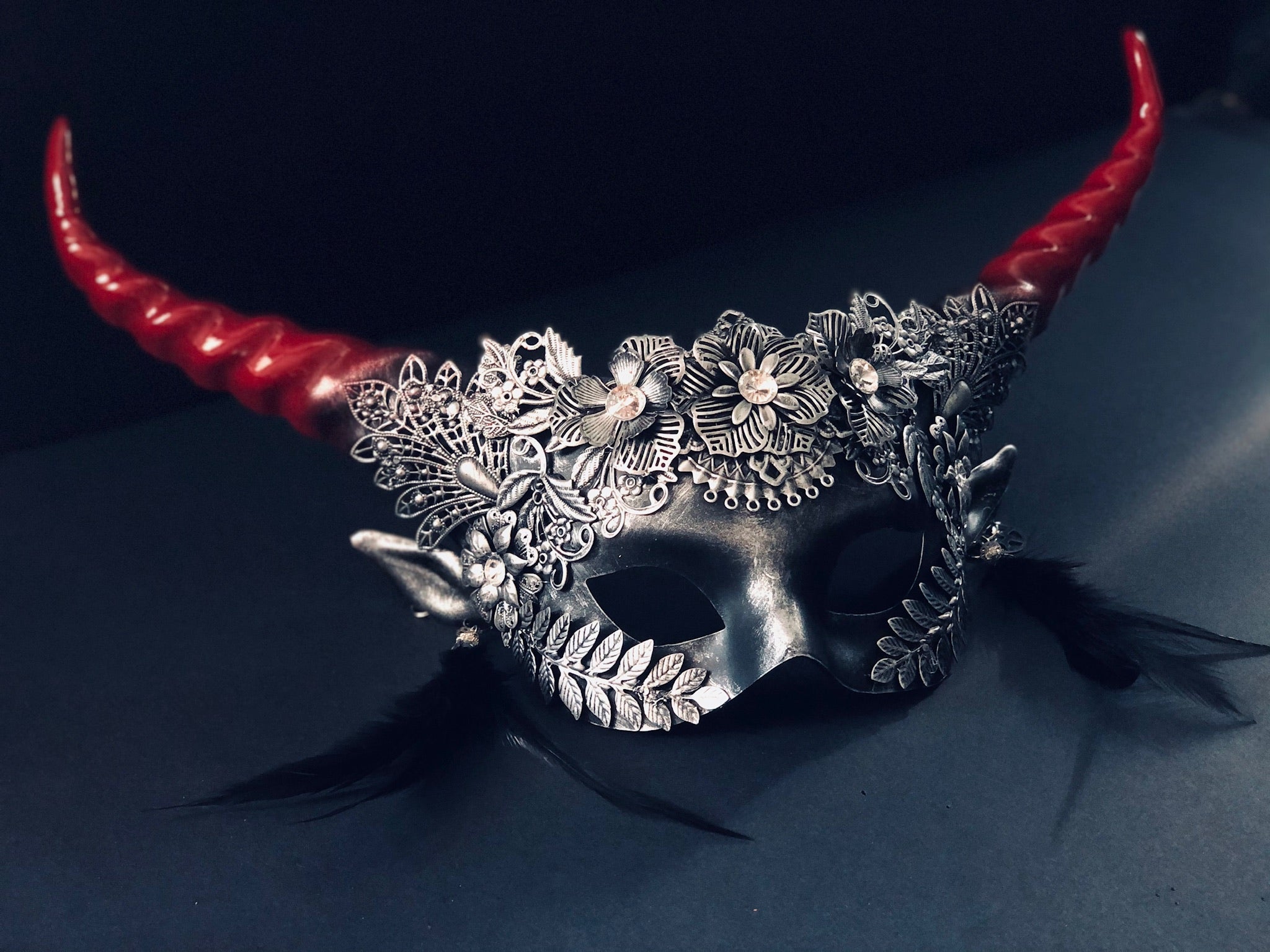 Metallic flower masquerade mask with spiral horns in red and silver.