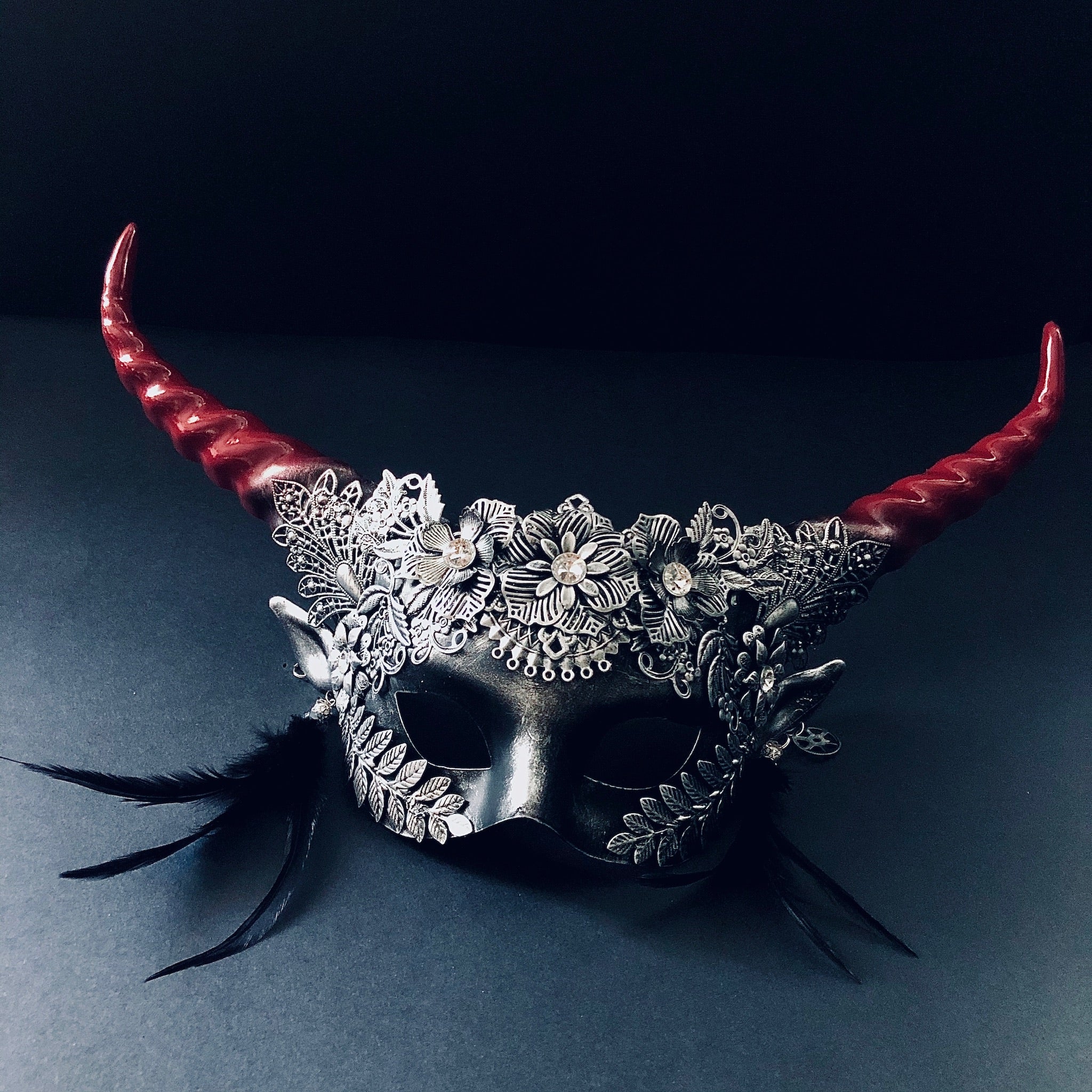 Metallic flower masquerade mask with spiral horns in red and silver.