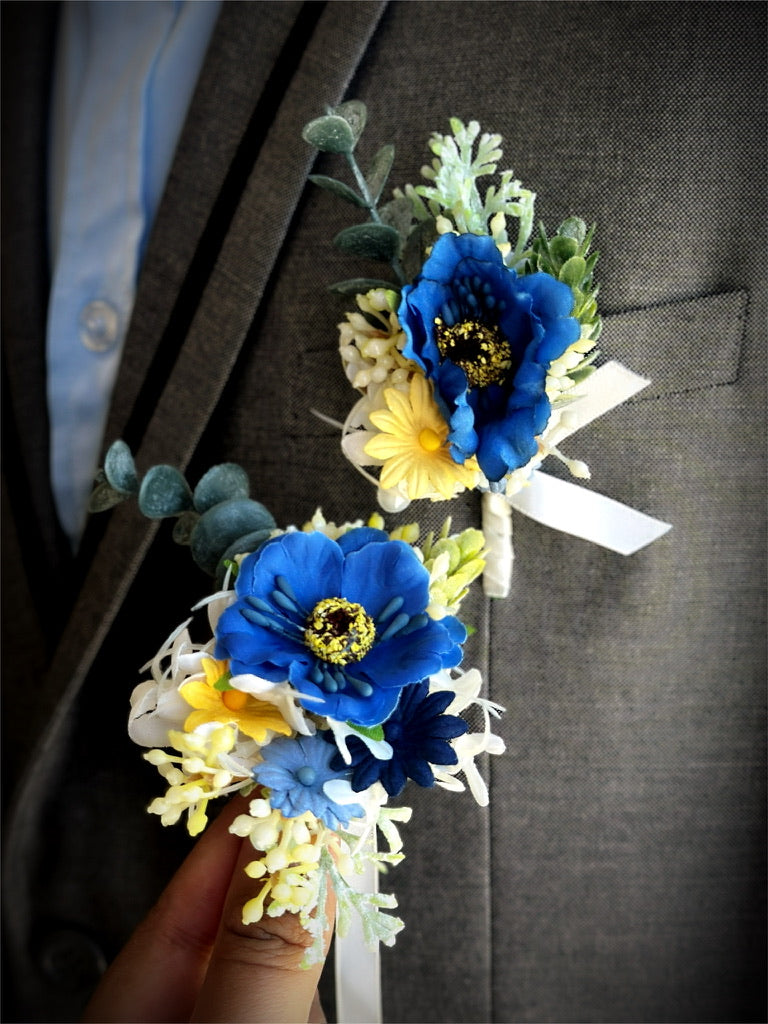Bright blue and yellow prom boutonniere and corsage set with greenery