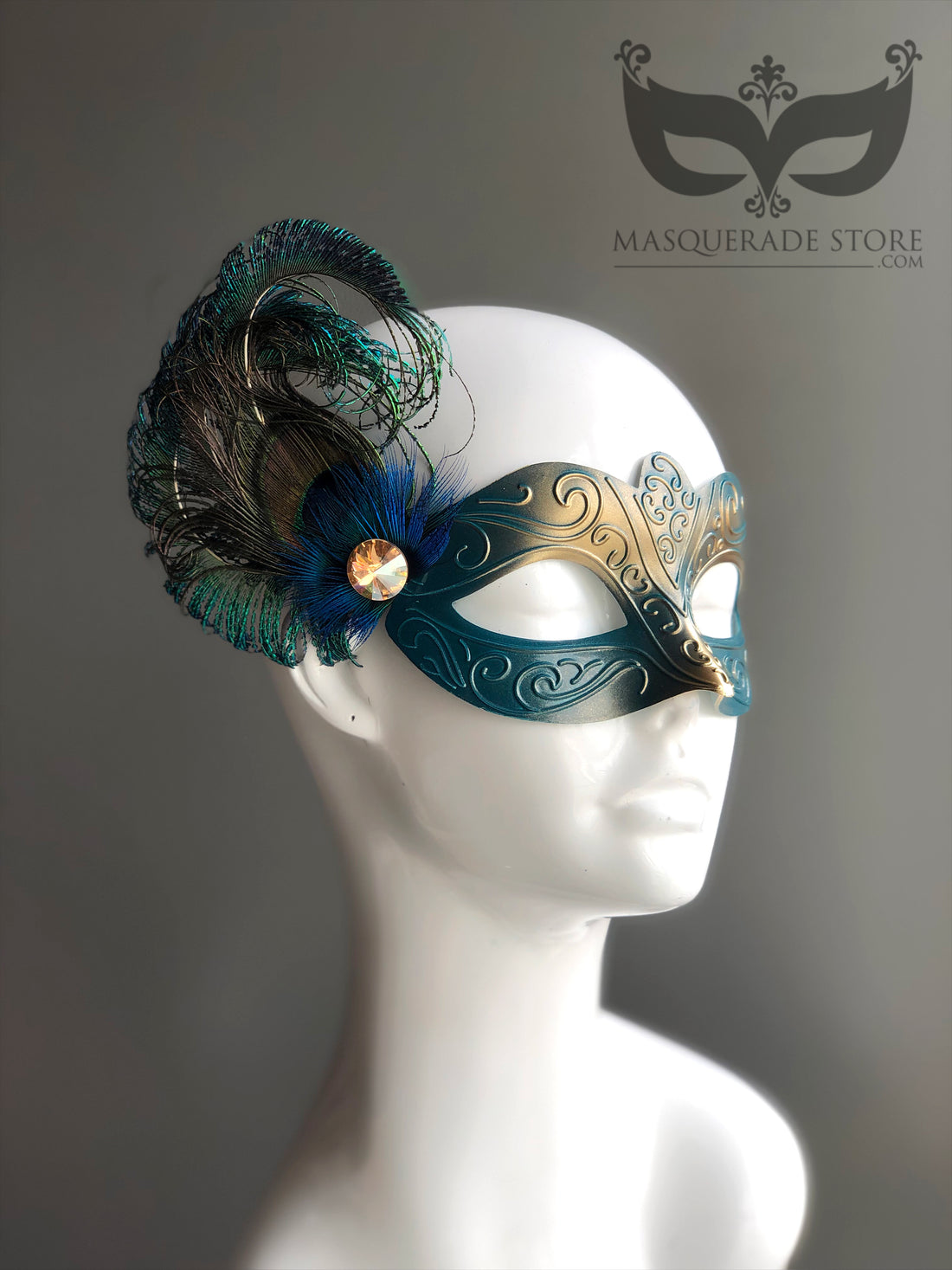 Teal and gold masquerade mask with intricate detailing, peacock feathers, and a crystal embellishment.