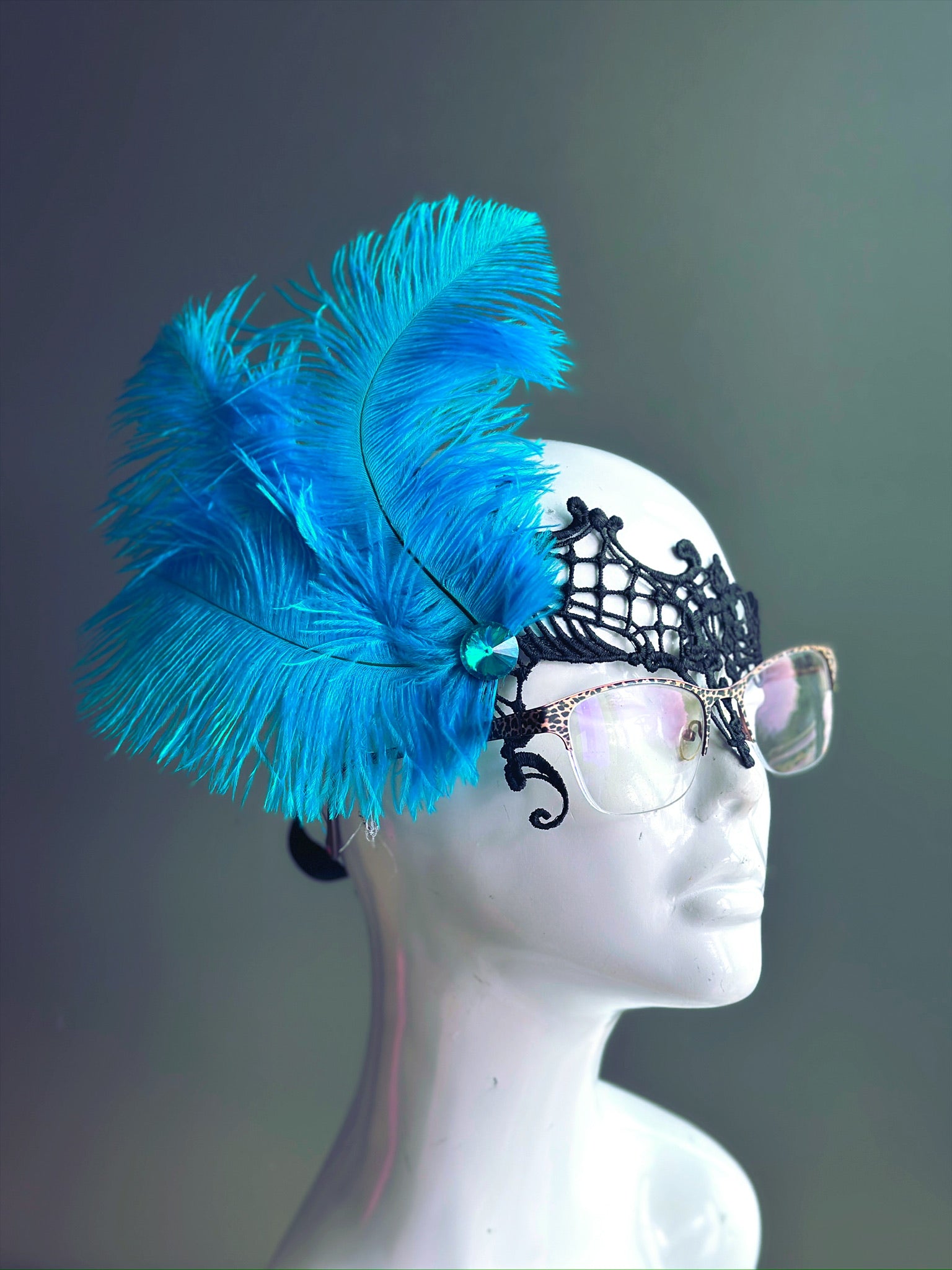 Turquoise Feather Masquerade Mask with black lace, designed to fit over glasses, adorned with vibrant turquoise feathers.
