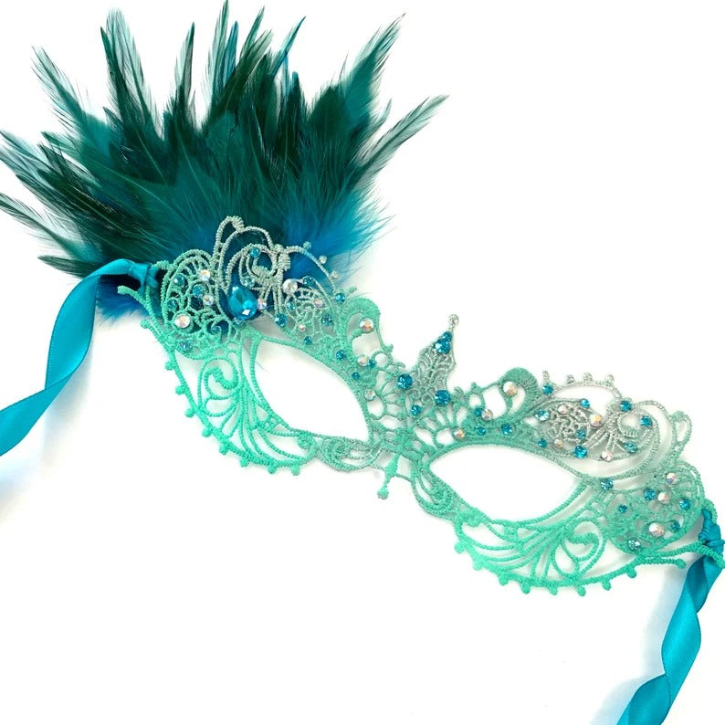 Elegant turquoise masquerade mask with lace, feathers, and rhinestone details for costume balls and Mardi Gras.