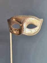 Gold handheld masquerade mask with ornate scroll design and stick handle