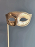 Gold handheld masquerade mask with ornate scroll design and stick handle
