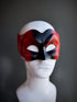 Venetian-style devil mask in black and red with a dramatic sculpted design, displayed on a mannequin.