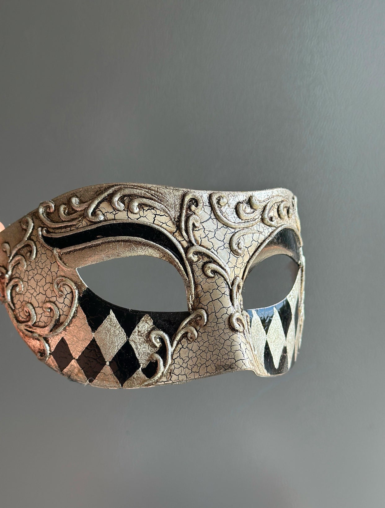 Venetian mask with antique crackle finish, scrollwork detailing, and black and silver harlequin patterns, ideal for masquerades and formal occasions.