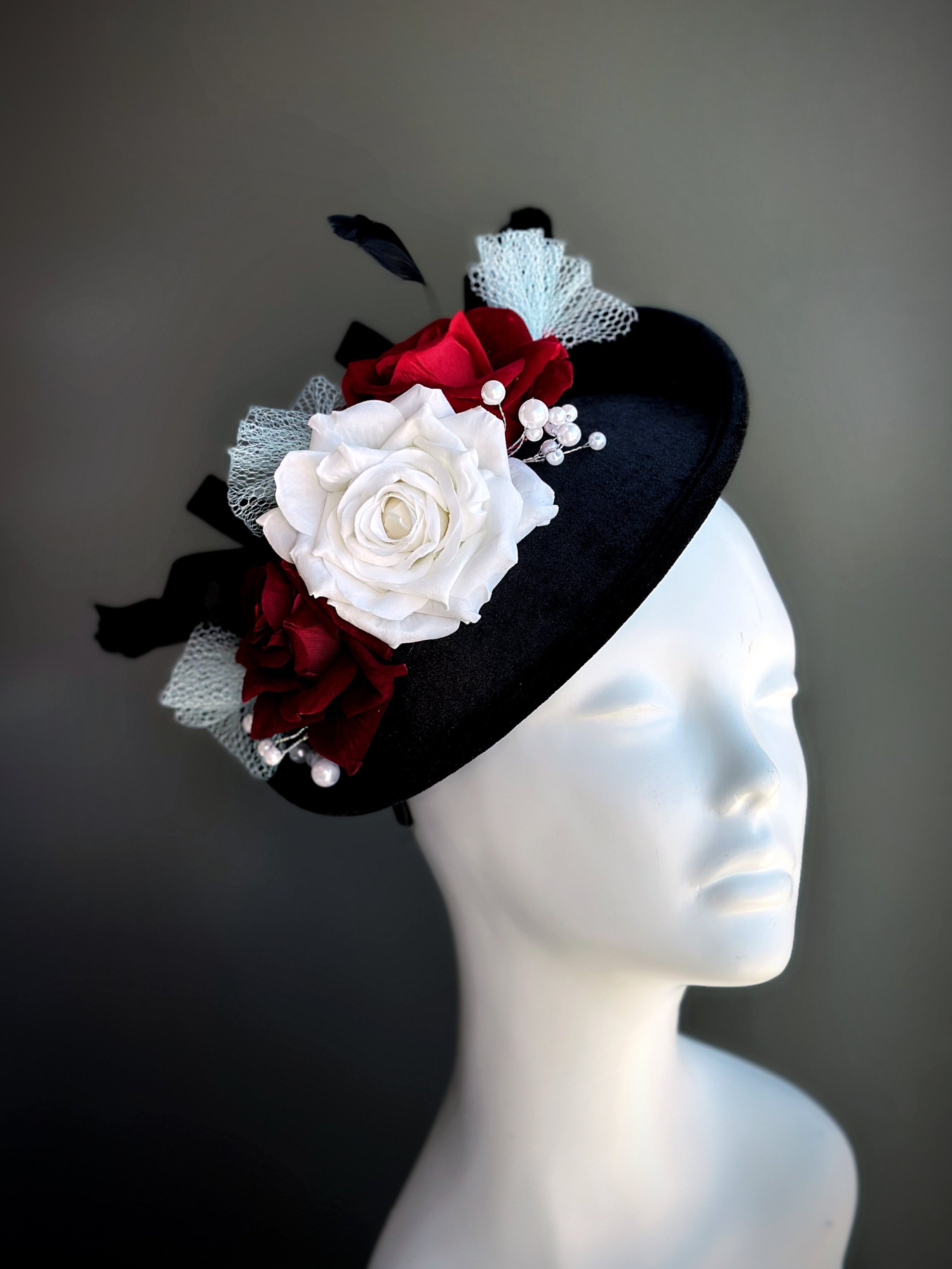 Vintage-style black velvet fascinator hat with red and white roses and pearl accents
