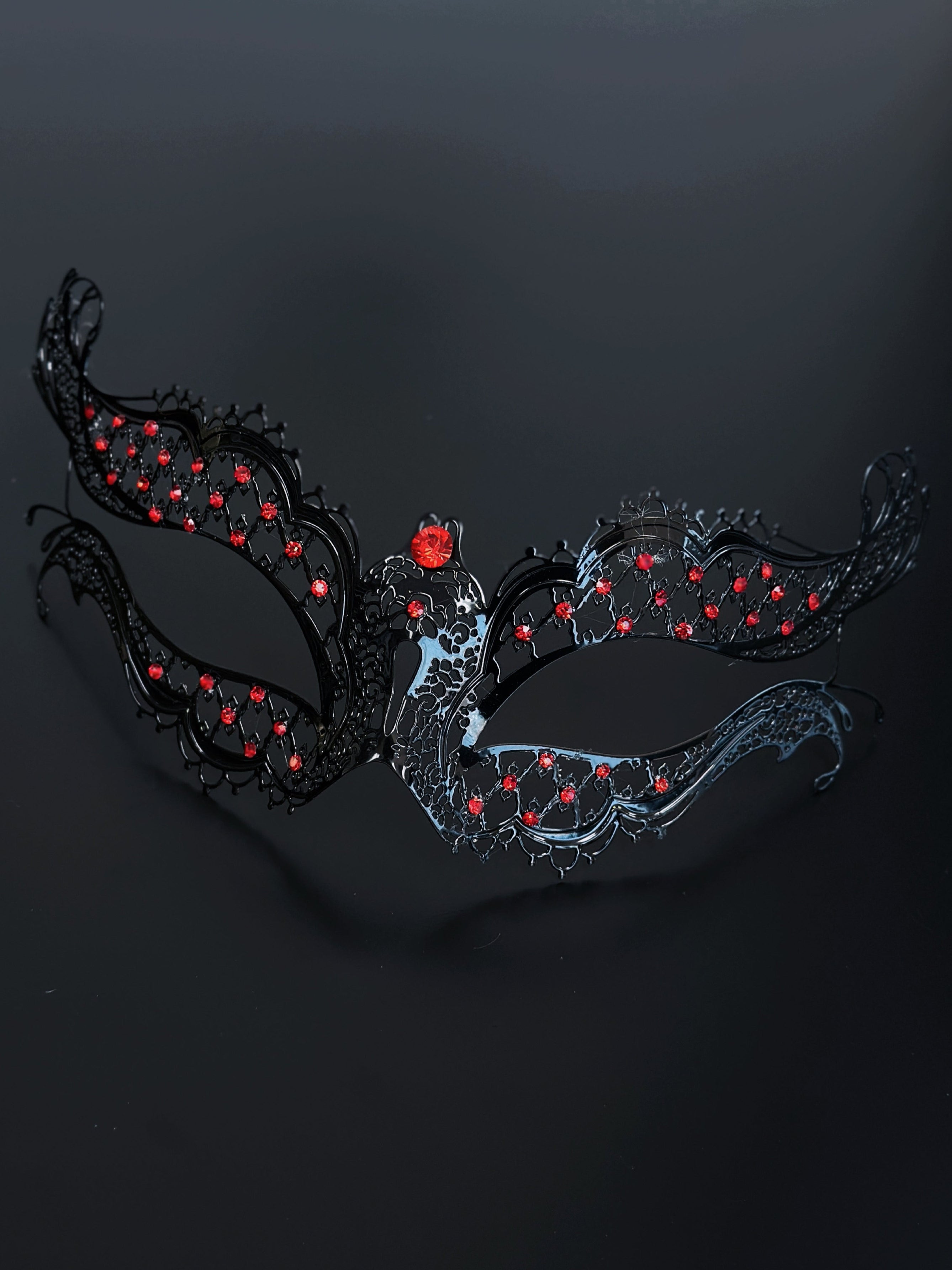 Black metal masquerade mask with ruby red rhinestones.