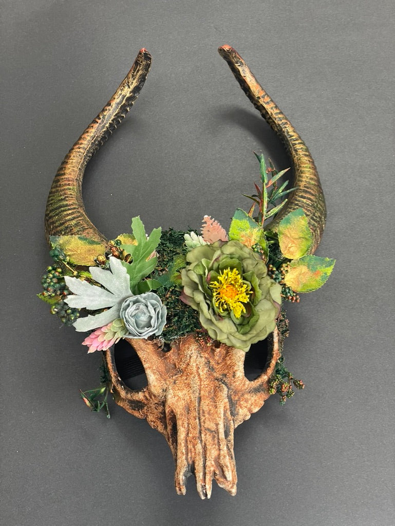 Fantasy woodland ram skull headdress featuring sculpted curved ram horns, faux flowers, moss, berries, and forest greenery. Ideal for Halloween, fantasy cosplay, Renaissance fairs, LARP, pagan festivals, woodland weddings, theatrical performances, fairy festivals, medieval events, and nature-inspired costume photography.