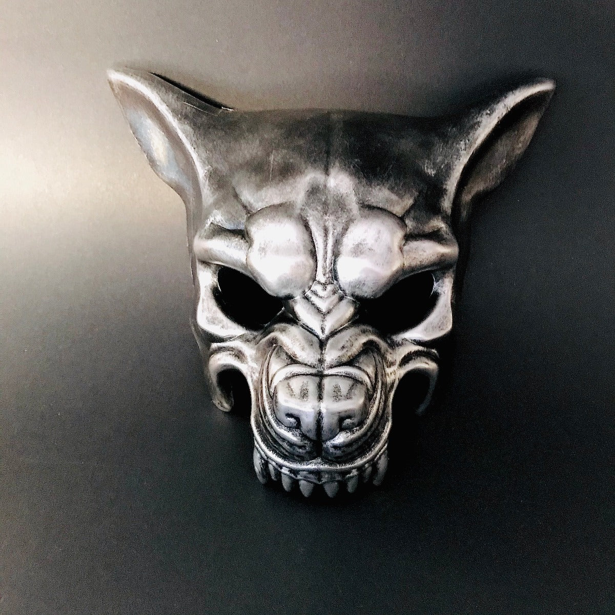 Metallic silver masquerade mask shaped like a wolf with dramatic contours