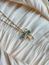 Gold bow pendant necklace with aqua gemstone accents on a twisted gold chain.