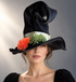 Autumn Garden Witch Hat with black velvet-style finish, sage satin ribbon, orange flower, green floral accent, and floppy brim.