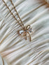 Gold bow pendant necklace with clear gemstone accents on a twisted gold chain.
