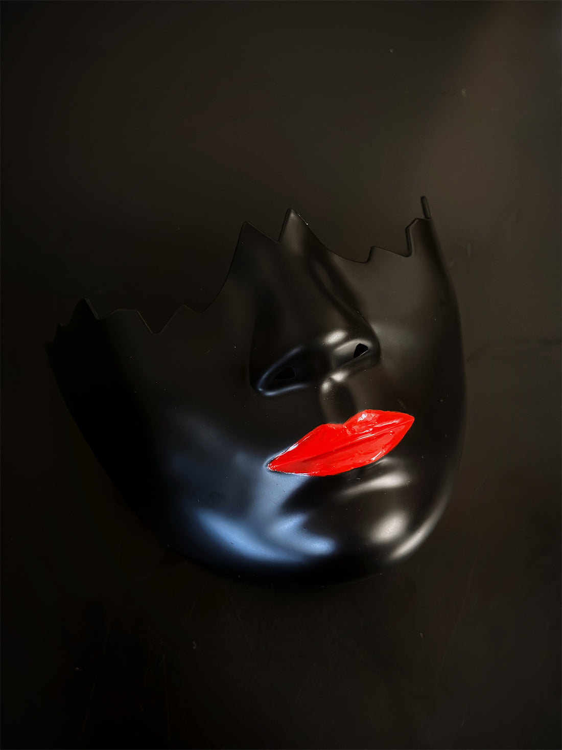 Glossy red lip mask with broken black face design for modern Halloween or costume looks