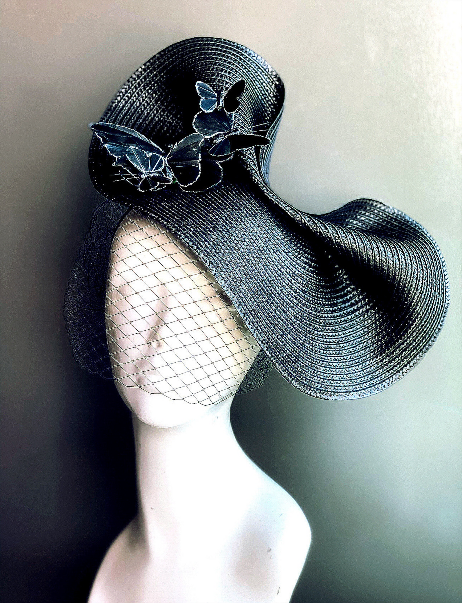 Black fascinator hat with butterfly accents and netted veil for gothic Halloween or masquerade fashion.