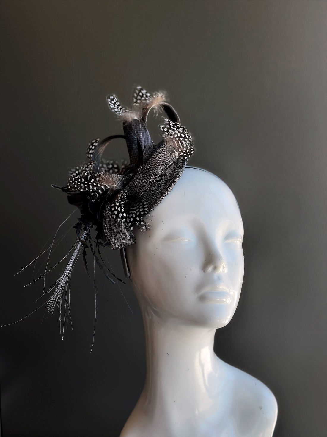 Black fascinator hat with curled loops and spotted feathers, ideal for Derby, tea parties, and weddings